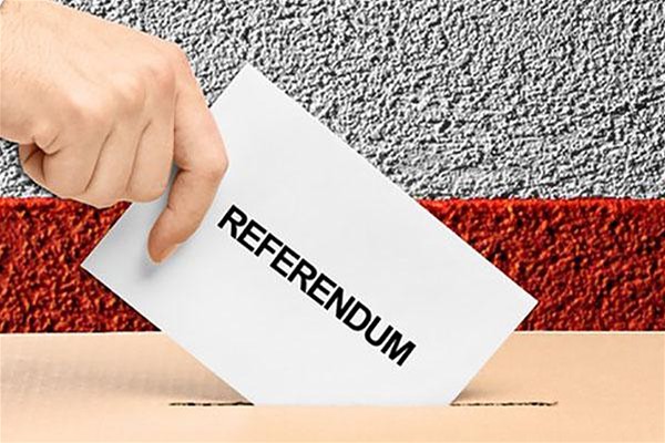 Mano che introduce dentro l'urna per le votazioni una scheda elettorale bianca con una scritta referendum.