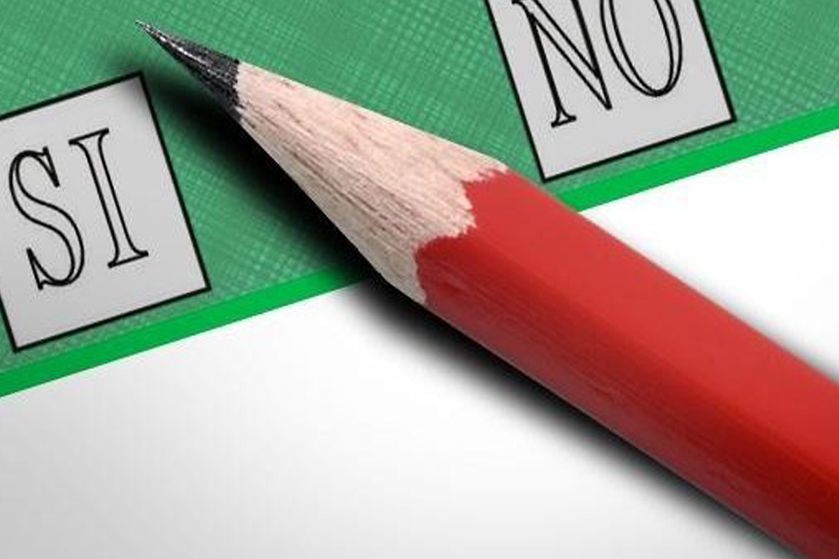 Scheda elettorale di colore verde a sinistra casella con la scritta SI a destra casella con scritta NO nel mezzo alle casella cè una matita