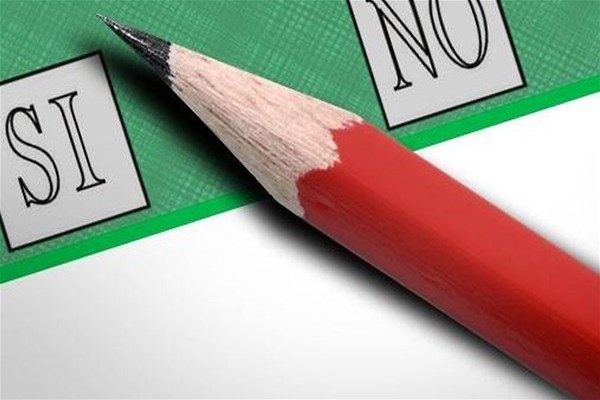 Scheda elettorale di colore verde a sinistra casella con la scritta SI a destra casella con scritta NO nel mezzo alle casella cè una matita